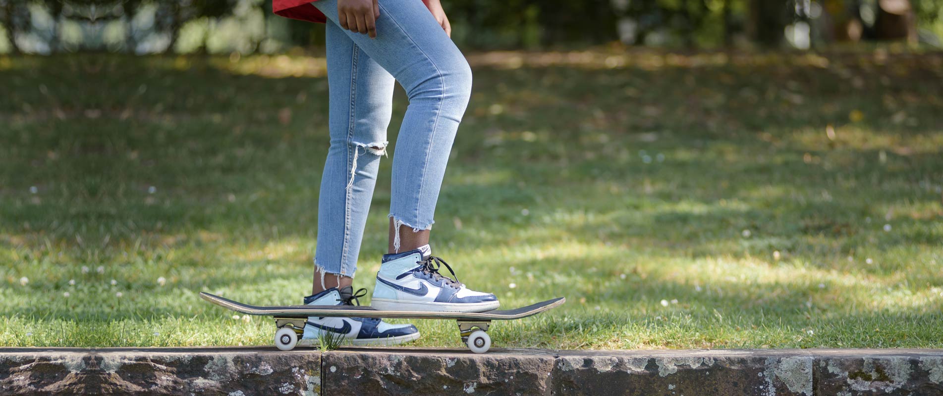Beine auf einem Skateboard vor einer Wiese