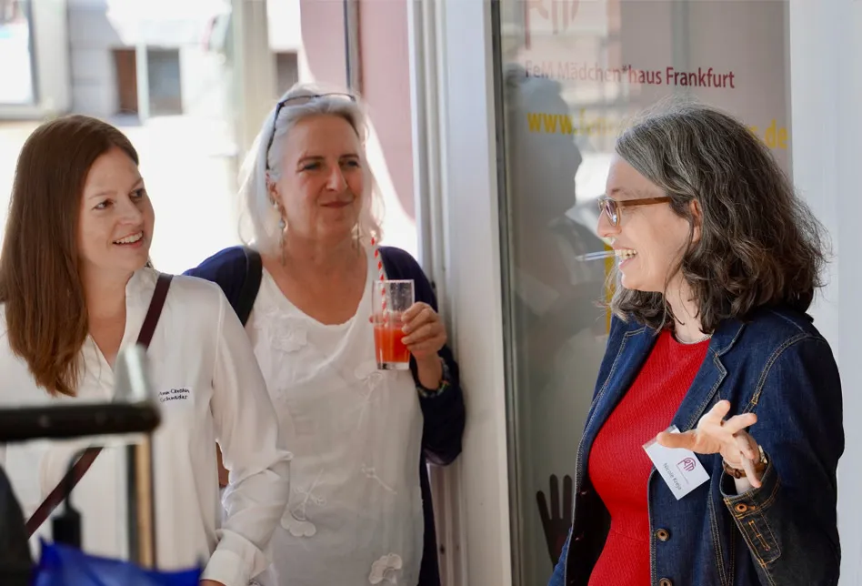 Im Eingangsbereich des fem-Mädchentreffs unterhalten sich drei Frauen sehr angeregt.