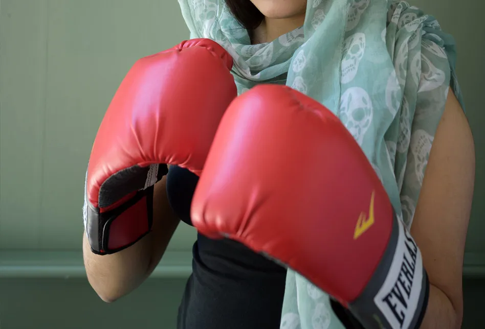 Ein Mädchen trägt Boxhandschuhe, bereit zum Angriff oder zur Verteidigung.